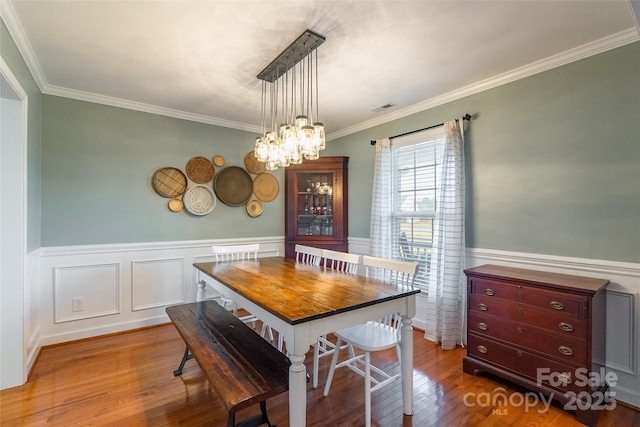 dining room with a chandelier, wood-type flooring, and ornamental molding