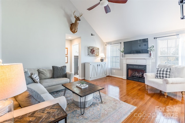 living room with hardwood / wood-style flooring, high vaulted ceiling, and ceiling fan