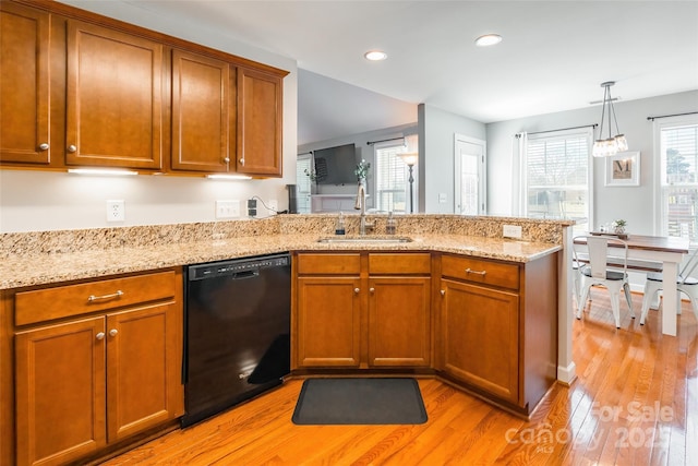 kitchen with kitchen peninsula, sink, light hardwood / wood-style flooring, black dishwasher, and hanging light fixtures