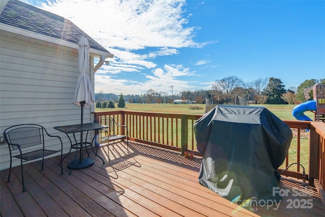 deck with a playground, a grill, and a yard