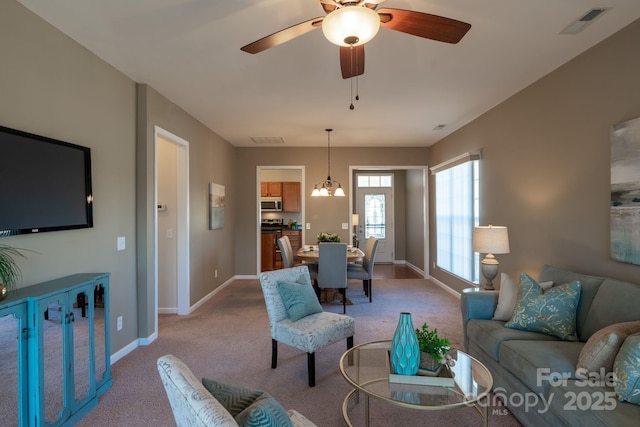 living room with light carpet and ceiling fan with notable chandelier