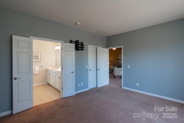 unfurnished bedroom featuring a closet, ensuite bathroom, and light carpet