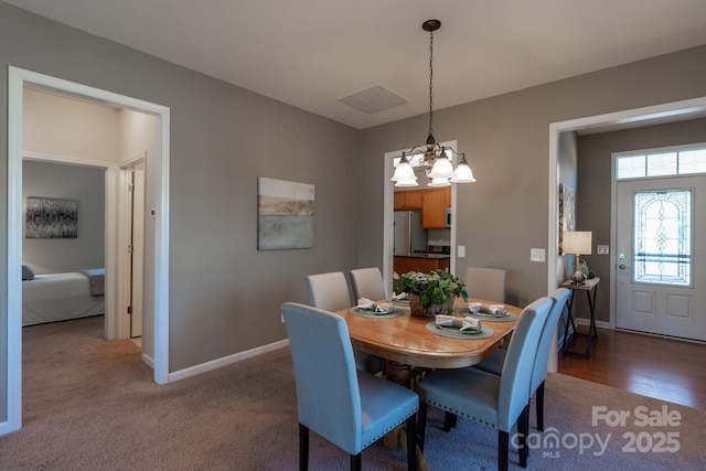 dining area with a chandelier and dark carpet