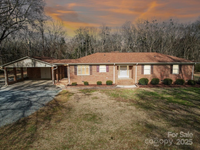 ranch-style home featuring a carport and a yard