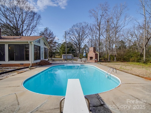 view of pool with a patio area, a diving board, and an outdoor fireplace