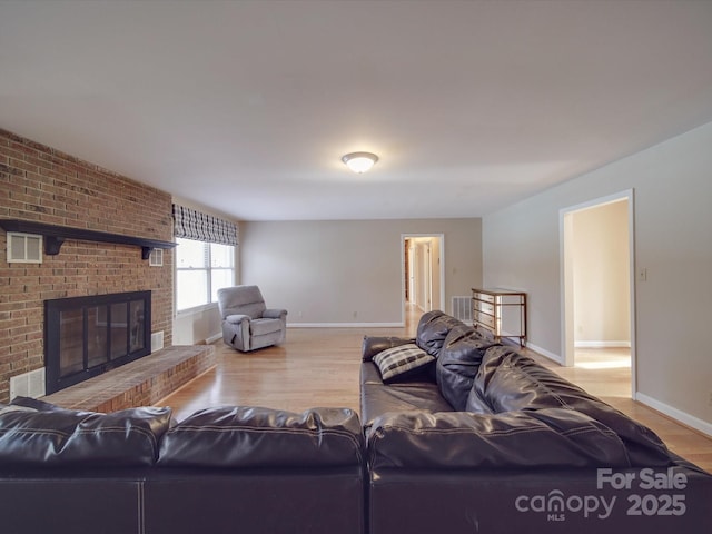 living room featuring light wood-type flooring and a brick fireplace