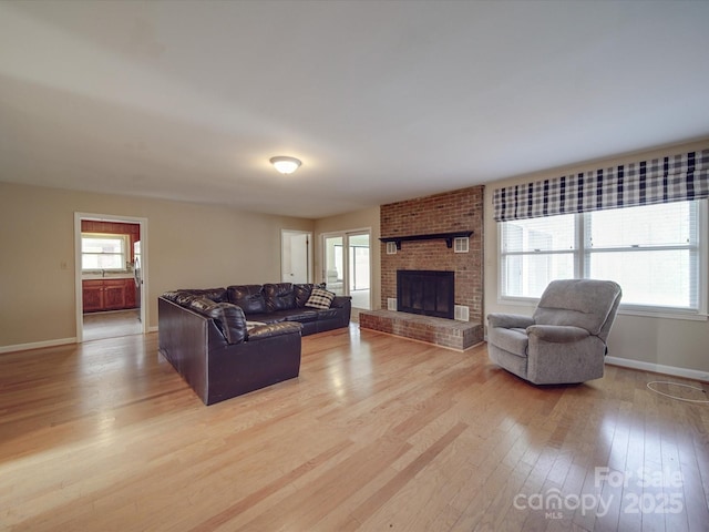 living room with a brick fireplace and light hardwood / wood-style floors