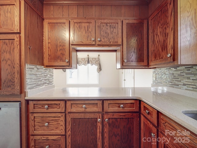 kitchen featuring light stone countertops, backsplash, and dishwashing machine