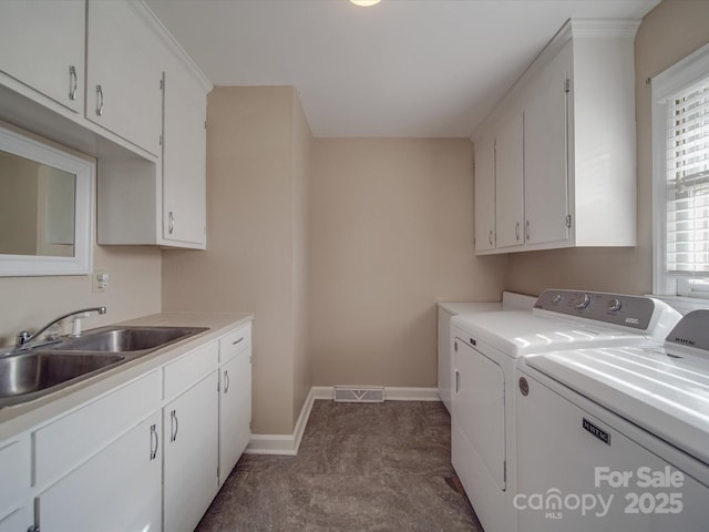 laundry area featuring cabinets, separate washer and dryer, and sink