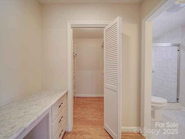 interior space featuring a shower with shower door, toilet, and hardwood / wood-style floors