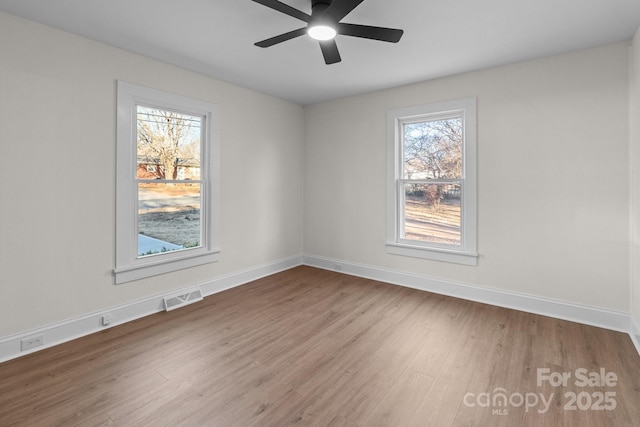 empty room with ceiling fan, a healthy amount of sunlight, and hardwood / wood-style floors