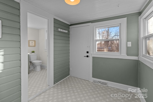 entryway featuring wood walls and ornamental molding