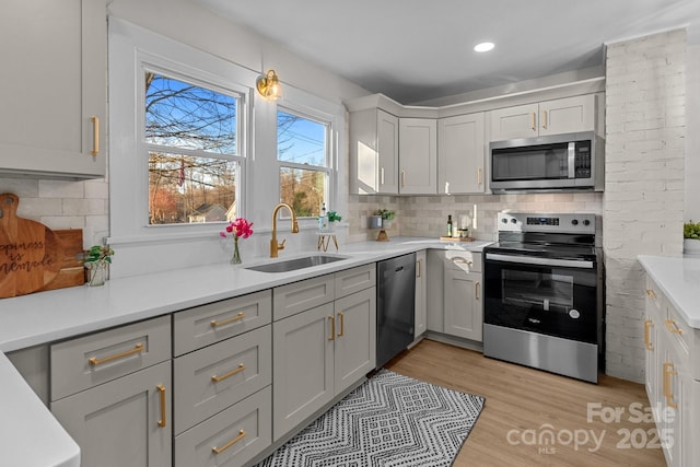 kitchen featuring tasteful backsplash, appliances with stainless steel finishes, sink, and light hardwood / wood-style flooring