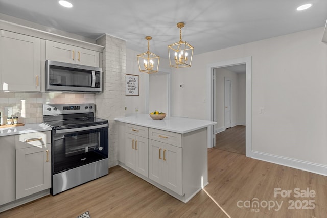 kitchen with appliances with stainless steel finishes, backsplash, hanging light fixtures, a chandelier, and light wood-type flooring