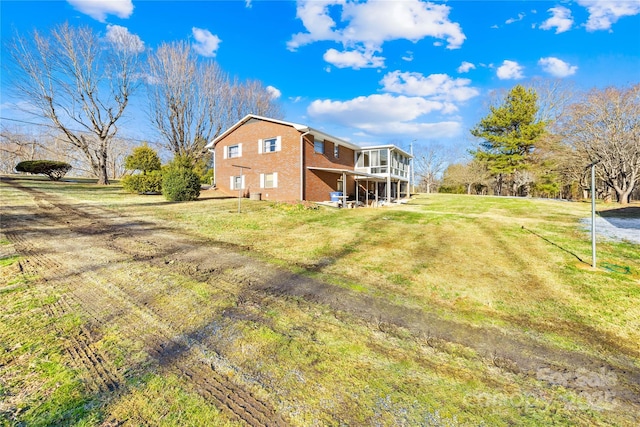 back of property with a lawn and a sunroom