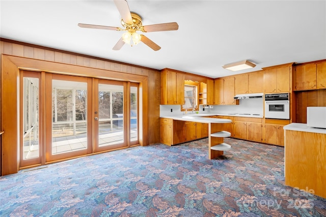 kitchen featuring white appliances, wood walls, ceiling fan, french doors, and sink