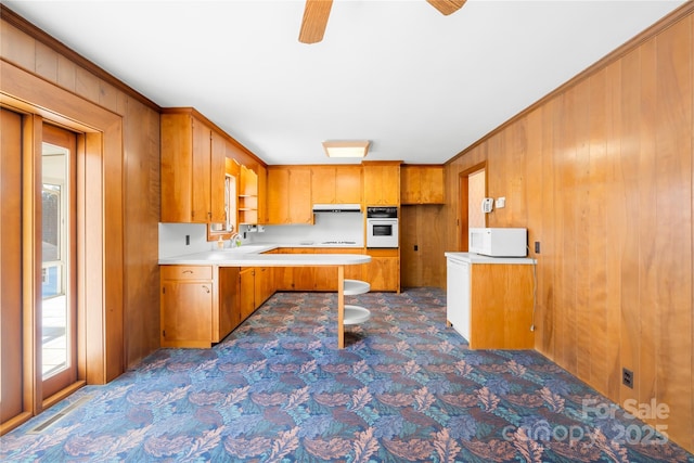 kitchen with white appliances, ornamental molding, wood walls, and ceiling fan