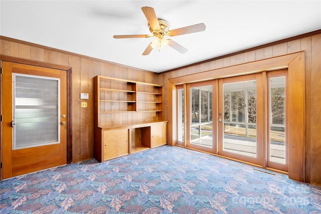 interior space with ceiling fan, french doors, and wooden walls