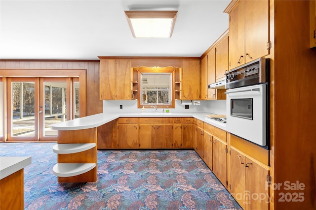 kitchen featuring white oven, french doors, kitchen peninsula, and sink