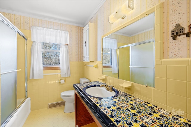 full bathroom featuring toilet, vanity, tile patterned floors, ornamental molding, and tile walls