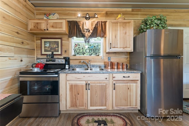 kitchen with appliances with stainless steel finishes, wooden walls, and sink