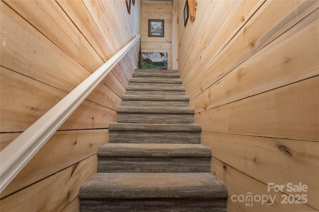 staircase featuring wooden walls