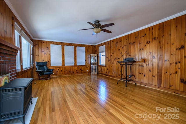 unfurnished room with light hardwood / wood-style floors, ceiling fan, wooden walls, and crown molding