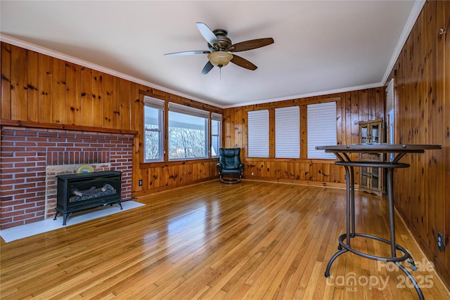 misc room with ceiling fan, light wood-type flooring, crown molding, and wood walls