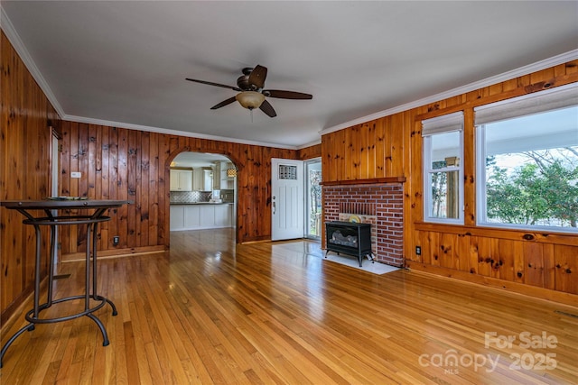 living room featuring ceiling fan, crown molding, a wood stove, and hardwood / wood-style floors