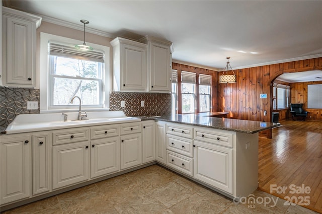 kitchen featuring kitchen peninsula, ornamental molding, white cabinets, and pendant lighting