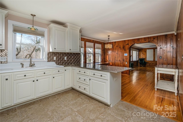 kitchen with kitchen peninsula, crown molding, a wealth of natural light, and hanging light fixtures