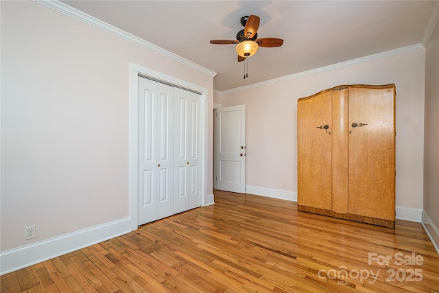 unfurnished bedroom featuring ornamental molding, ceiling fan, hardwood / wood-style flooring, and a closet