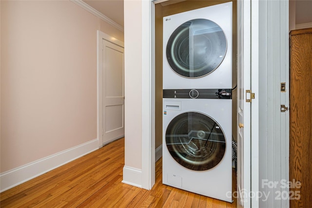 clothes washing area with crown molding, light hardwood / wood-style floors, and stacked washer / dryer