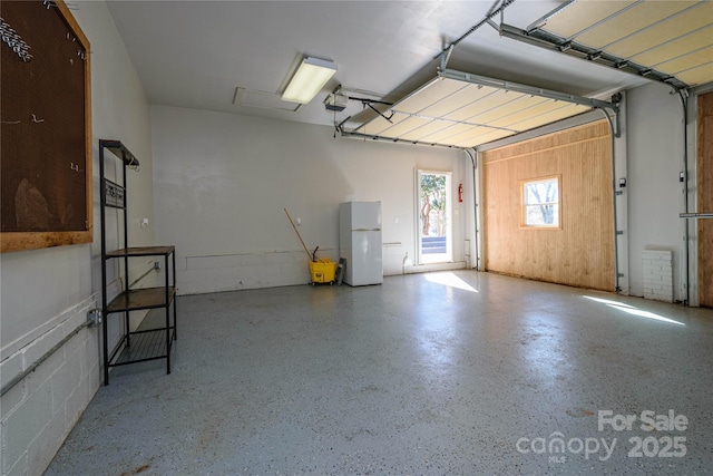 garage with a garage door opener and white refrigerator