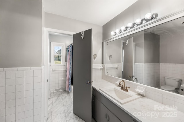 bathroom featuring vanity, tile walls, and toilet