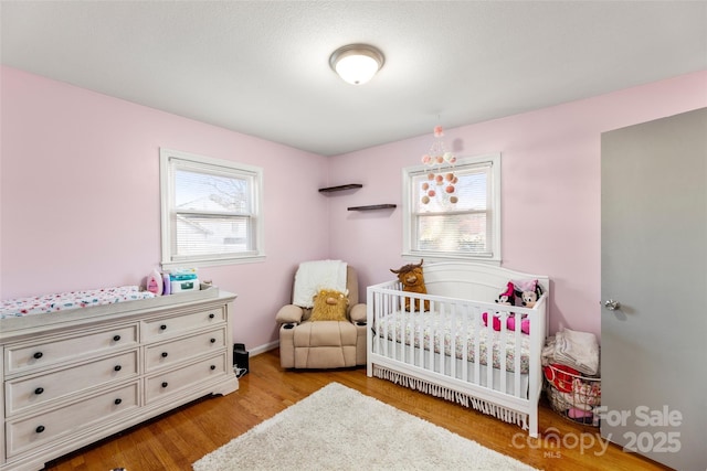 bedroom with light wood-type flooring and a nursery area