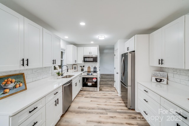 kitchen with white cabinets, decorative backsplash, sink, and stainless steel appliances