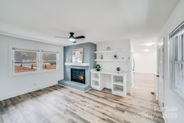 living room with light hardwood / wood-style flooring, a brick fireplace, and ceiling fan