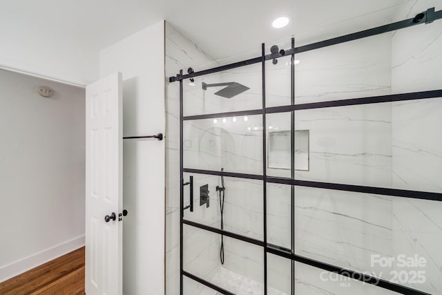 bathroom featuring tiled shower and wood-type flooring