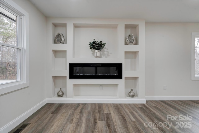 unfurnished living room with built in shelves and hardwood / wood-style flooring