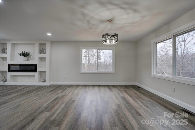 unfurnished living room with dark wood-type flooring, built in features, and a chandelier