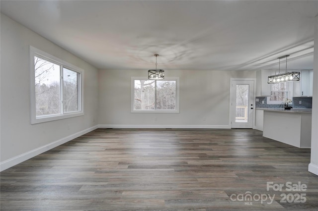 unfurnished dining area featuring an inviting chandelier and dark hardwood / wood-style flooring