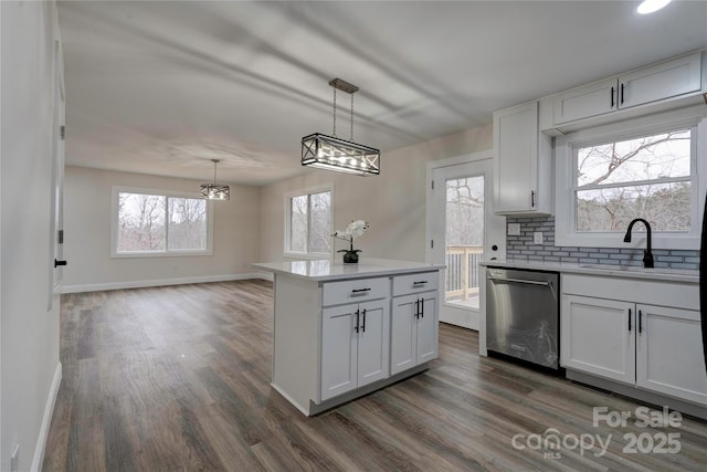 kitchen with sink, decorative light fixtures, white cabinetry, stainless steel dishwasher, and a kitchen island