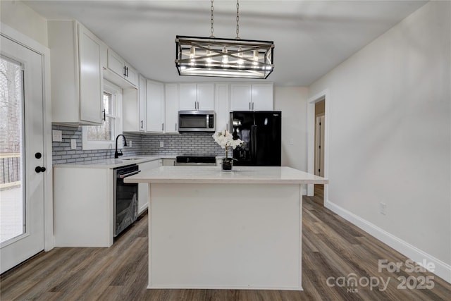 kitchen featuring a center island, decorative light fixtures, black appliances, white cabinetry, and sink