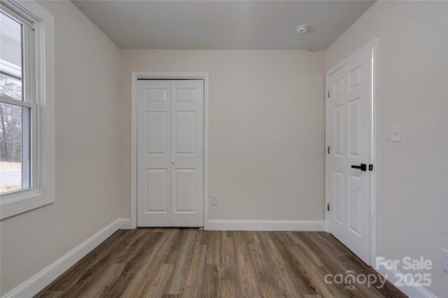 unfurnished bedroom with a closet and dark hardwood / wood-style floors