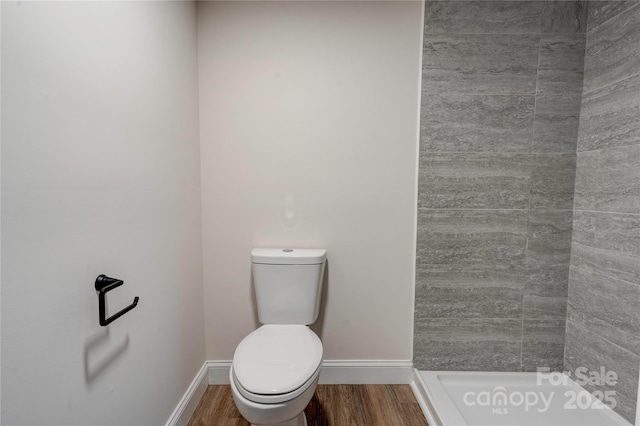 bathroom featuring hardwood / wood-style floors, a shower, and toilet