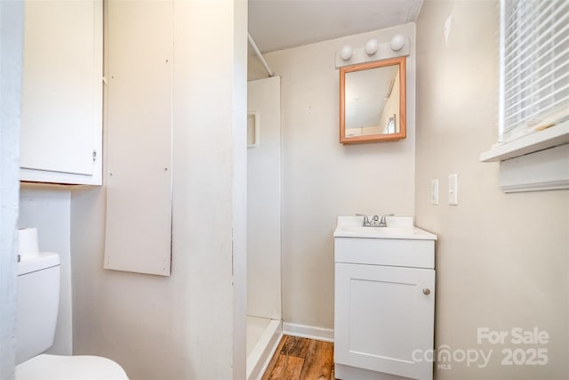 bathroom with walk in shower, vanity, hardwood / wood-style flooring, and toilet