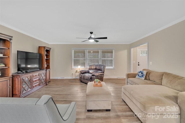 living room with light wood-style flooring, crown molding, baseboards, and ceiling fan