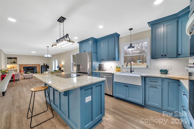 kitchen featuring a sink, blue cabinets, appliances with stainless steel finishes, and open floor plan