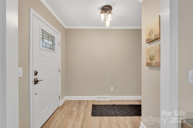 foyer featuring light wood-type flooring, baseboards, visible vents, and ornamental molding